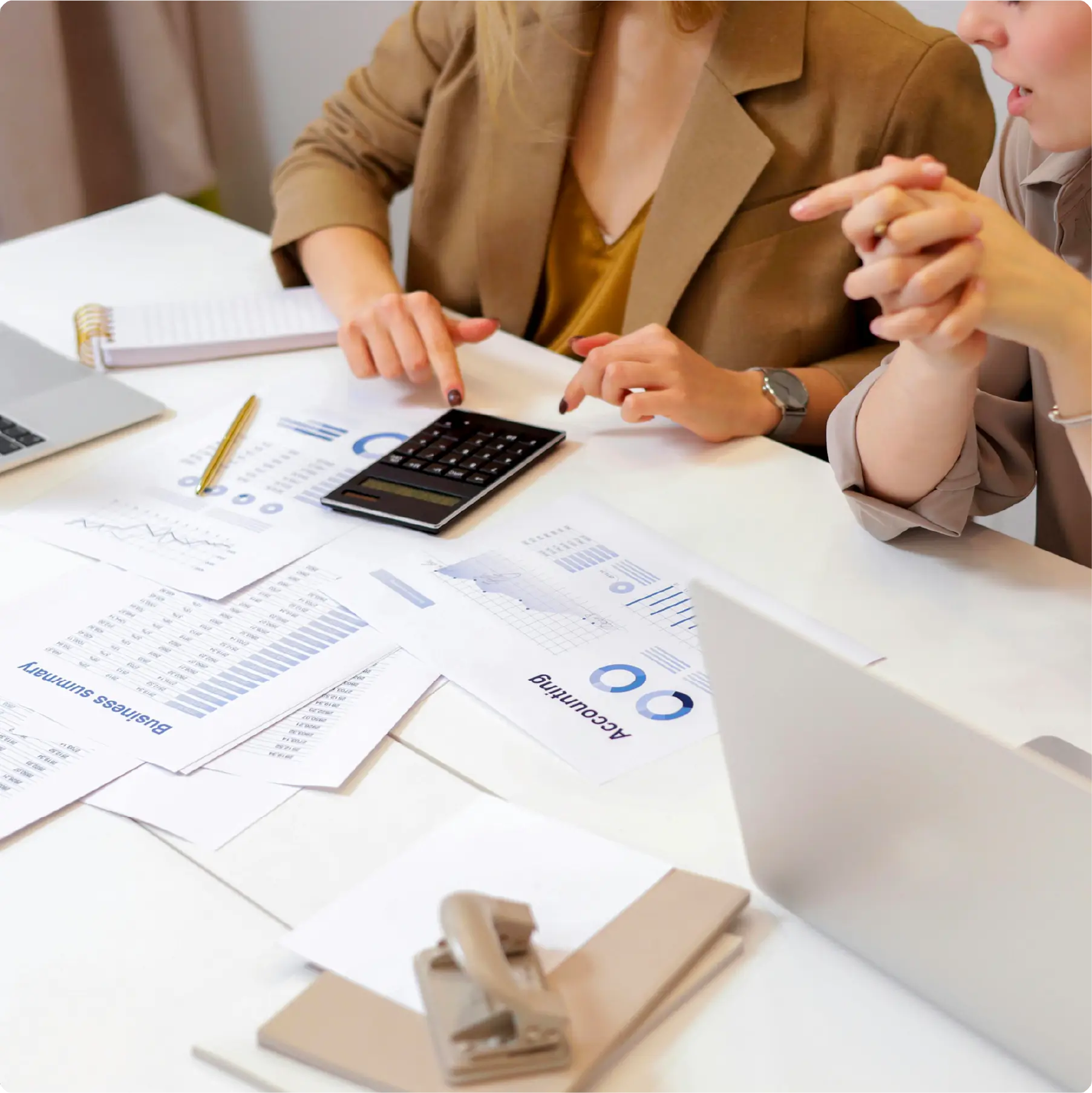 Two people working together using pieces of papers and a calculator