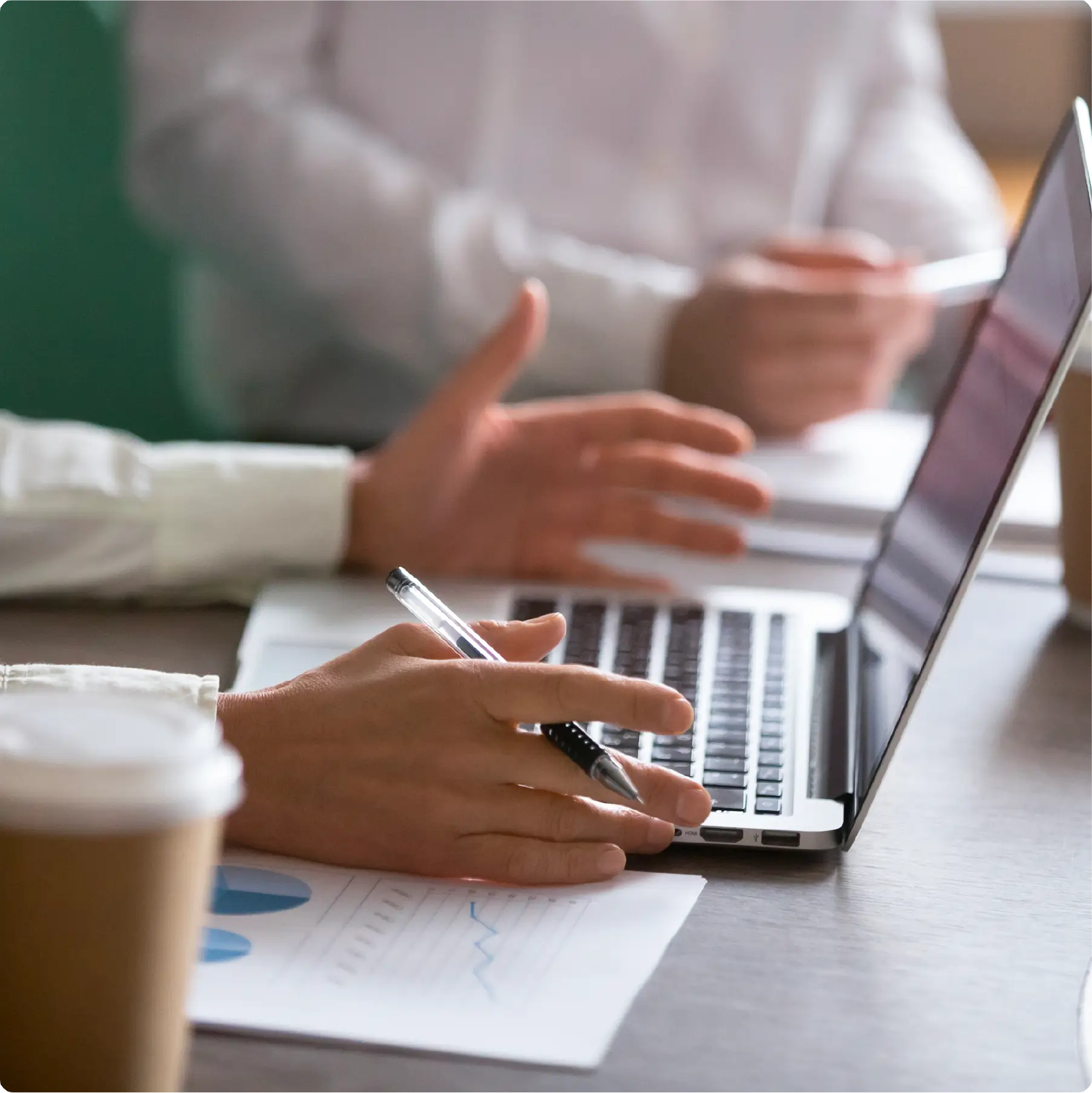A person holding a pen while in front of laptop