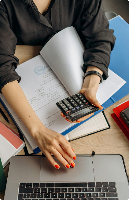 An employee holding a calculator while scrolling on the laptop