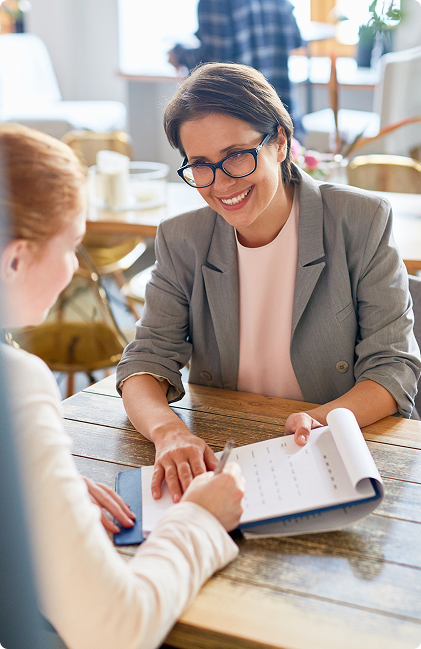 A woman talking on another woman, waiting for a sign on the paper