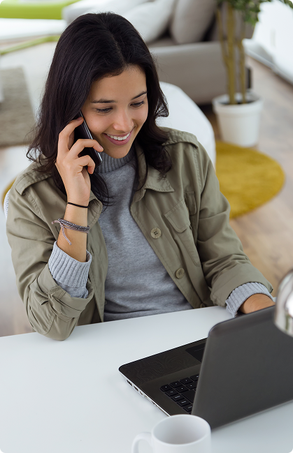 A person on phone smiling with laptop in front
